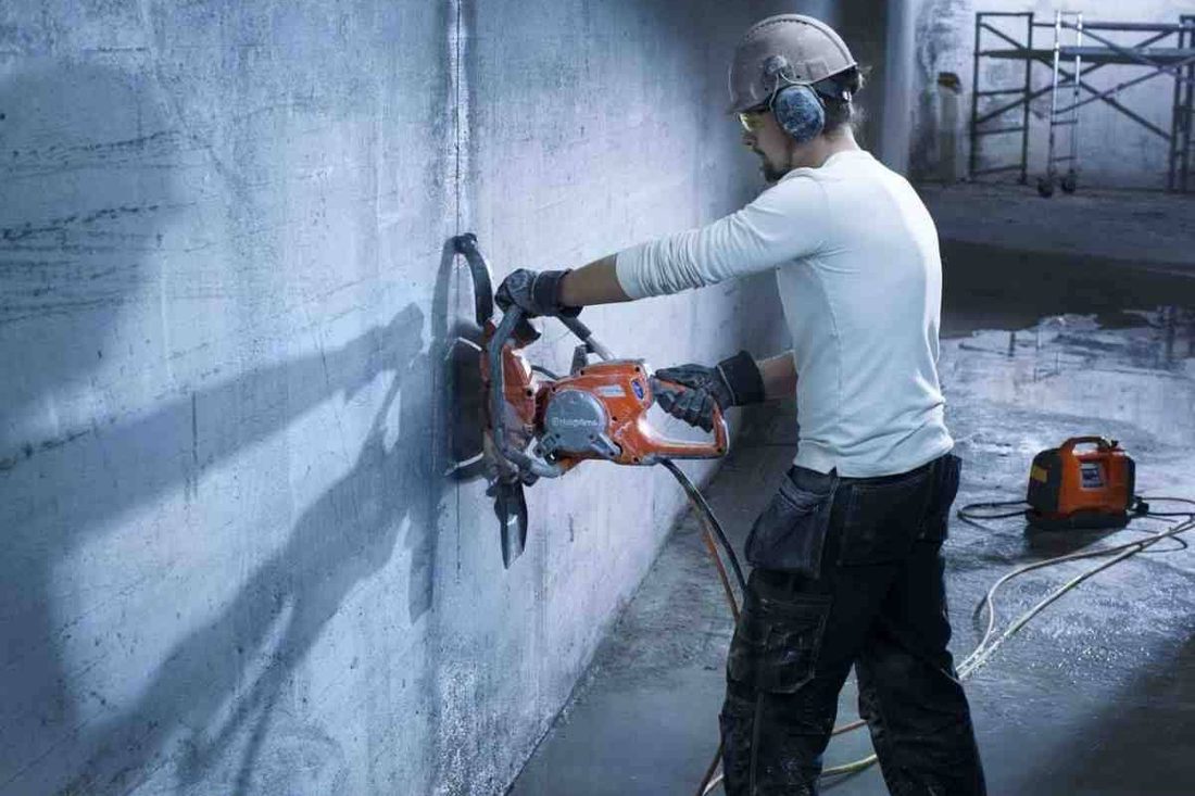 Worker cutting through a concrete wall on site